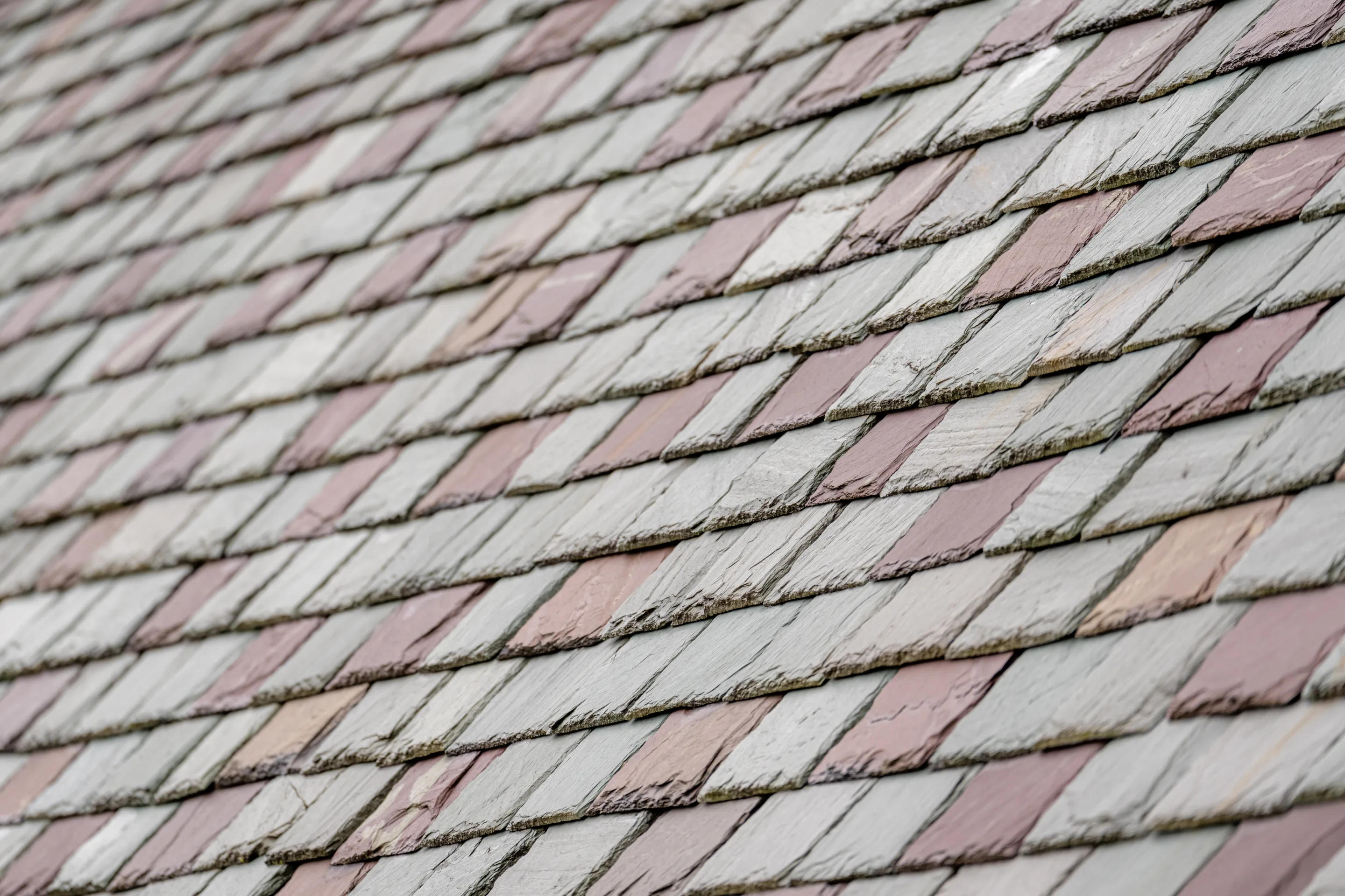 Macro view of variegated pink, cream, and grey natural slate shingles
